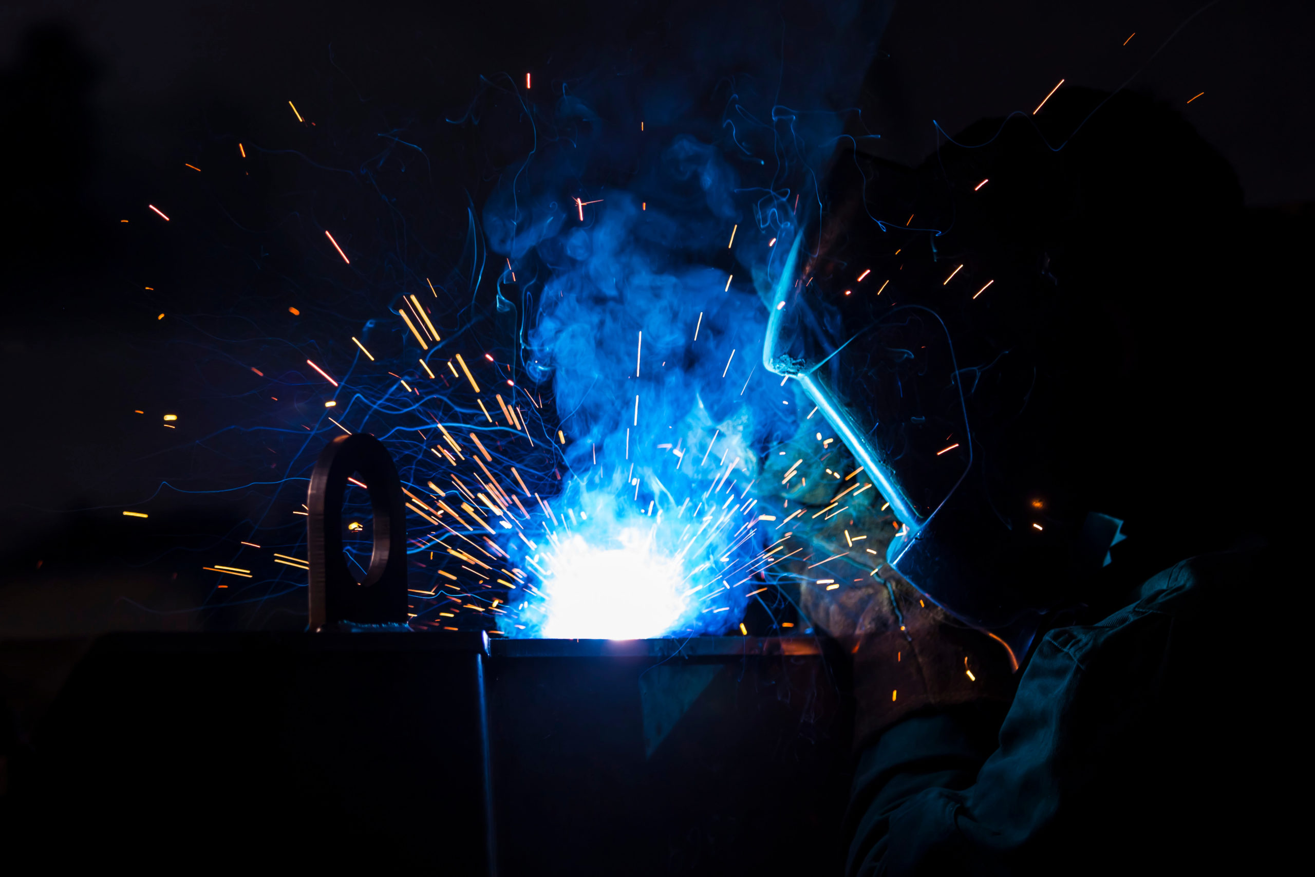 Young industrial worker welding in the factory